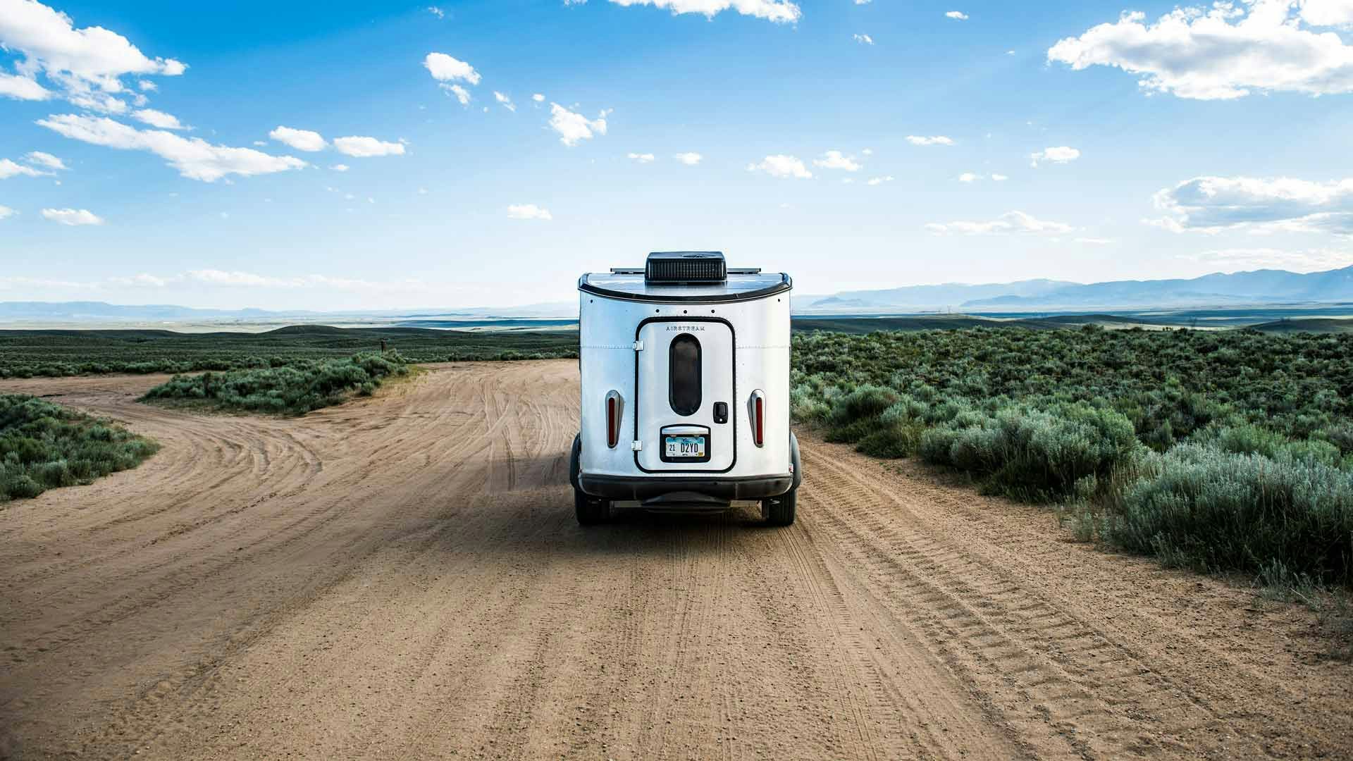 Airstream Basecamp on Dirt Road in Front of Blue Sky
